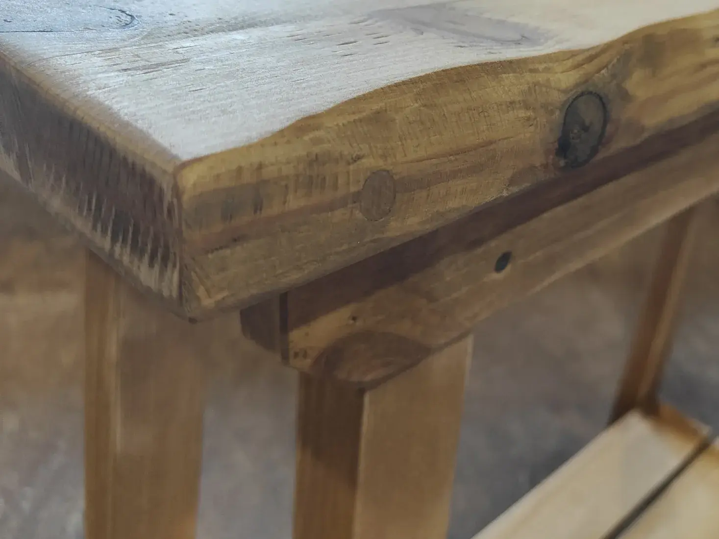 Close view of a hand-distressed solid wood furniture edge with rustic patina and visible grain