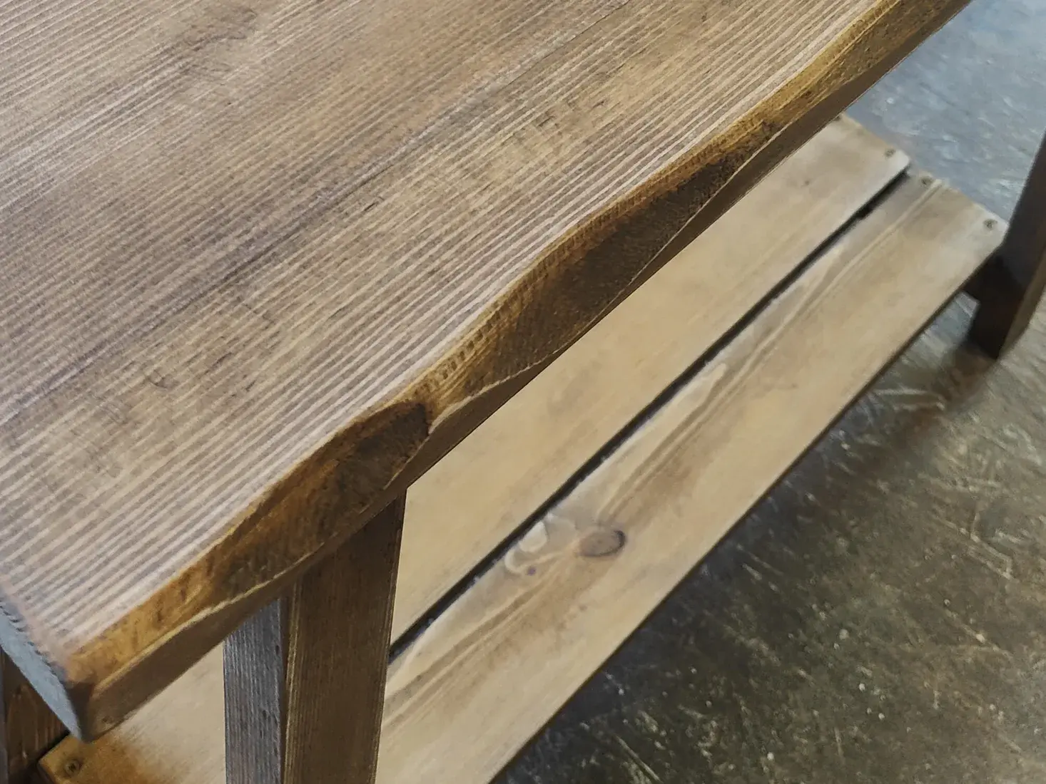 Rustic solid wood furniture surface with visible grain, softened edges and hand-distressed finish detail