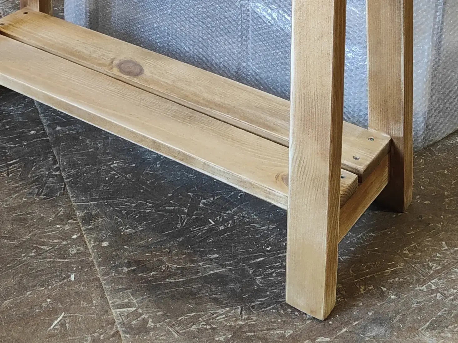 Hand-finished lower shelf and leg detail on rustic solid wood furniture