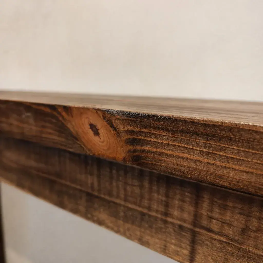 Close-up of rustic solid pine console table edge and dark wood grain texture
